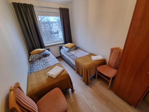Cette chambre dispose de deux lits, d'une chaise et d'une fenêtre. dans l'établissement Apartament Olszewskiego, à Wrocław