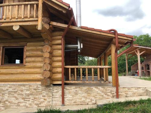 a log cabin with a porch and a deck at Casa din Deal in Moldoveneşti