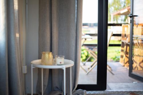 ein Tisch mit einem Glas neben einer Tür in der Unterkunft Houten huisje tussen paarden in Nieuwerkerken