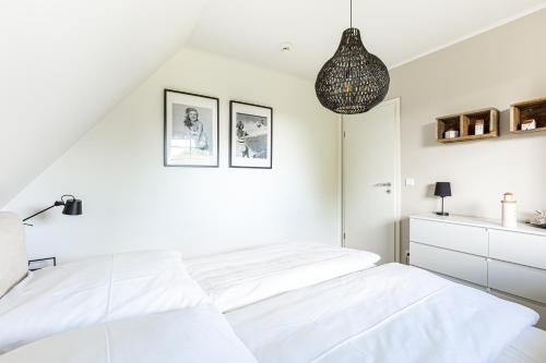 a white bedroom with two beds and a pendant light at Schöne Aussichten in Wieck