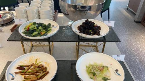 three plates of food on a table with plates of food at Hilton Garden Inn Jinzhou Central Street in Jinzhou