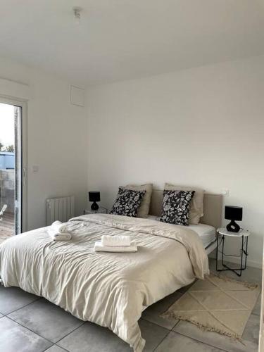 ein weißes Schlafzimmer mit einem großen Bett und 2 Tischen in der Unterkunft Maison 90m2 Lormont 3 chambres et jardin in Lormont