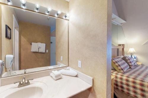 ein Bad mit einem Waschbecken, einem Spiegel und einem Bett in der Unterkunft The Lodge at Mountain Village Unit 308 A and B in Park City