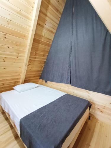 a bed in a wooden room with a black curtain at Mira bungalov rize in Ardeşen