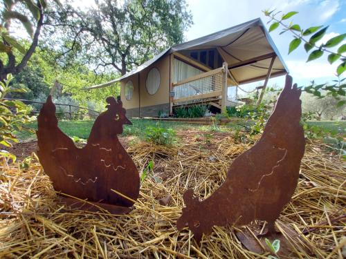 two chicken statues sitting in the hay in front of a house at Wine Glamping Le Sedici in Massa Marittima