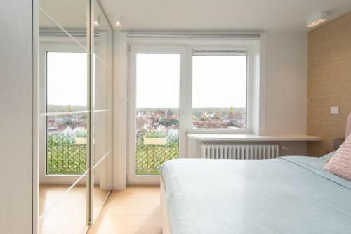 une chambre avec un lit et deux grandes fenêtres dans l'établissement Panne-O-Rama, à La Panne