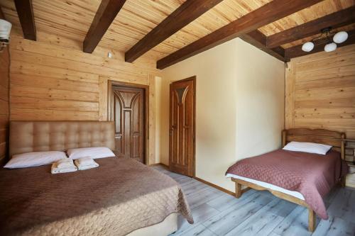 two beds in a room with wooden walls and wooden floors at Садиба у Кіри in Slavske