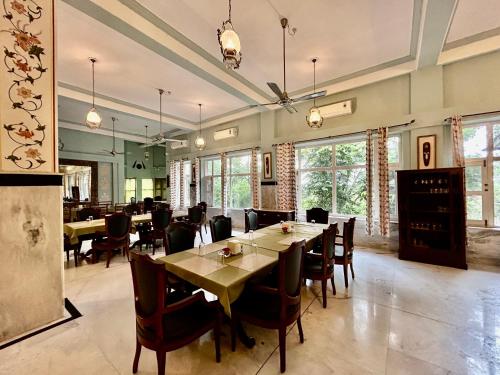DubbīUmaid Palace - A Lakeside Resort - 25 minutes from Mehandipur Balaji - 20 minutes from Chand Baori Stepwell Abhaneri & 40 minutes from Bhangarh Fort的有桌椅和窗户的餐厅