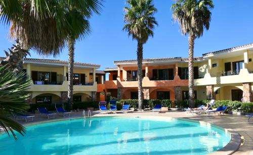 a swimming pool in front of a building with palm trees at ISA-apartments with air conditioning and outdoor private space in residence with swimming-pool in Palau, only 150 meters from the sea in Palau