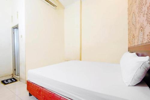 a bedroom with a white bed with a red frame at Wisma Idola Palopo in Palopo