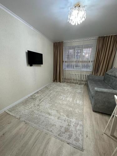 a living room with a couch and a television at Аэропорт 5 минут in Prigorodnyy