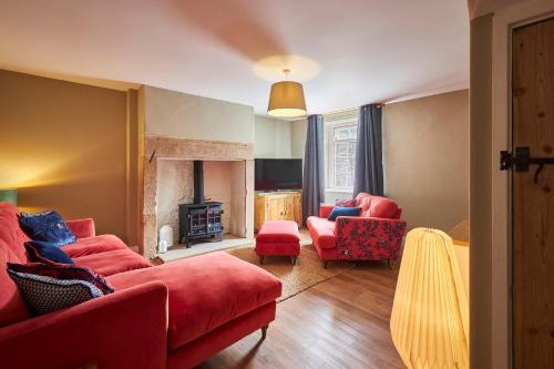 a living room with red furniture and a fireplace at Host & Stay - North Cottage in Newbrough