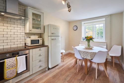 a kitchen with a table and a white refrigerator at Host & Stay - North Cottage in Newbrough