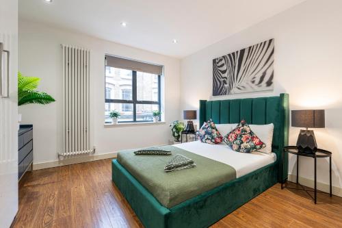 a bedroom with a large bed with a green headboard at Fashionable Brick Lane in London