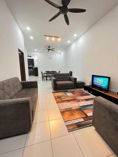 a living room with couches and a flat screen tv at NZAK Homestay, Melaka in Malacca