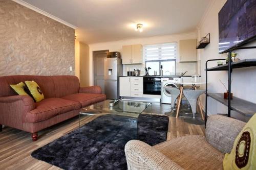 uma sala de estar com um sofá e uma mesa de vidro em Rondebosch Central em Cidade do Cabo