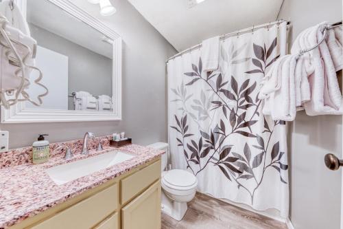 y baño con lavabo, aseo y cortina de ducha. en Sea Treasures Inn Units #205-212, en Rockaway Beach