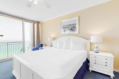 a bedroom with a large white bed and a balcony at Pearl 1602 in Navarre