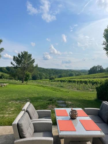 a patio with two couches and a table with a view at Le nid du vallon in Pomport