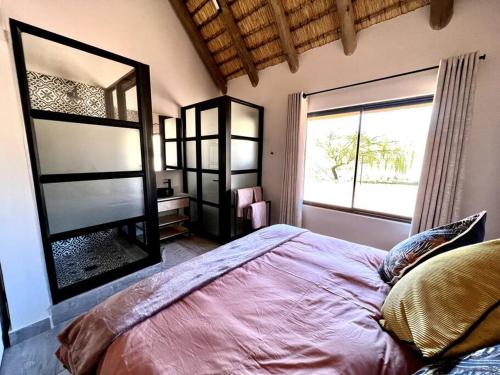 a bedroom with a large bed and a large window at The Fisherman's Cottage in Mooirivier