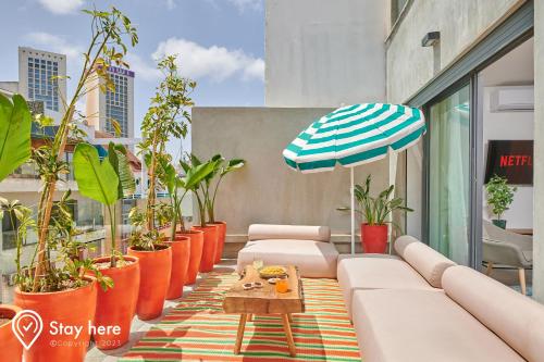 un patio con plantas, un sofá y una sombrilla en Stayhere Casablanca - Gauthier 2 - Contemporary Residence, en Casablanca
