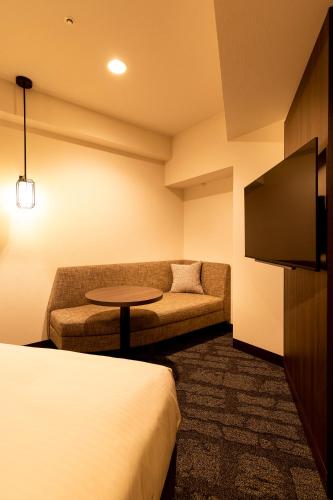 a hotel room with a couch and a tv at Hotel JAL City Nagano in Nagano