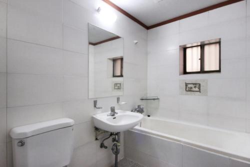 a white bathroom with a sink and a toilet and a tub at Dream of City Motel in Daegu