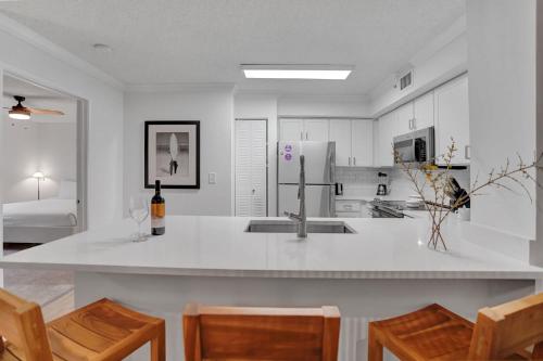 a kitchen with a sink and a counter with chairs at Stylish Modern Apartments at Gables Grand Plaza in Miami in Miami