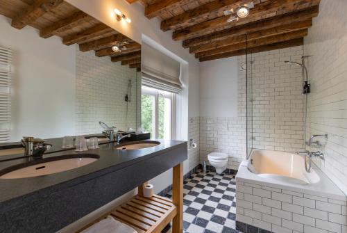 a bathroom with two sinks and a tub and a toilet at Fletcher Hotel Château De Raay in Baarlo