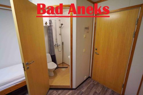 a bathroom with a toilet and a door with bad angels sign at Hattfjelldal Hotell in Hattfjelldal