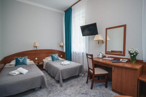 ザコパネにあるZespół Dolina Białego - Pensjonat Telimenaのベッド2台、デスク、鏡が備わる客室です。