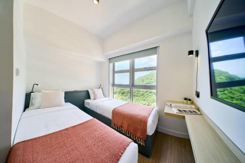 two beds in a room with a window at South Nest in Hong Kong