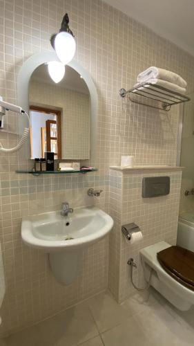 a bathroom with a sink and a mirror and a toilet at Bellapais Abbey Boutique Hotel in Kyrenia