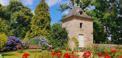 a stone tower in a garden with flowers at chateau du Bois-Riou in Quévert