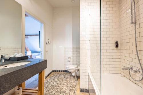 a bathroom with a tub and a toilet and a sink at Fletcher Hotel Château De Raay in Baarlo