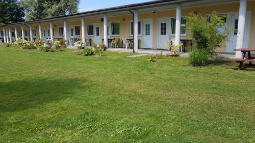 a building with a grass yard with a bench in front of it at POMERANIA Pokoje U Oliwii in Rewal