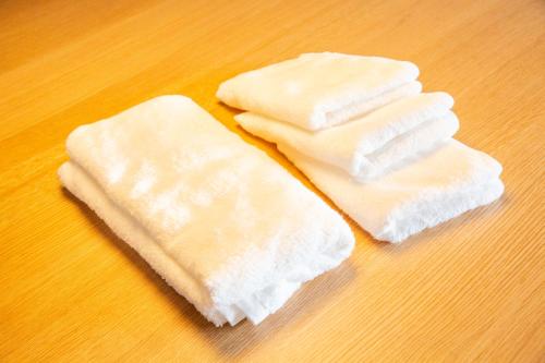 three white towels sitting on top of a wooden table at 町宿ORANCHI 