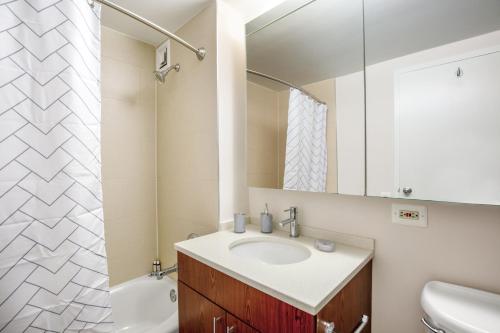 uma casa de banho com um lavatório e um espelho em Chelsea 1BR w Roof deck Gym Doorman NYC-122 em Nova York