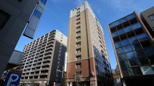 een hoog gebouw in een stad met twee hoge gebouwen bij Toyoko Inn Toride-eki Higashi-guchi in Toride
