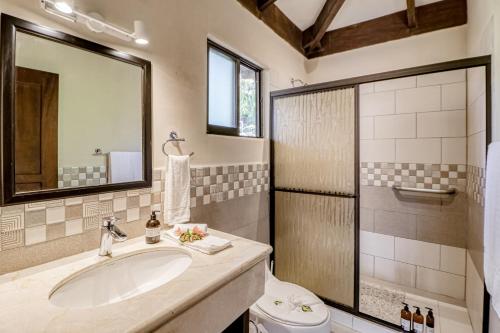 ein Badezimmer mit einem Waschbecken, einem WC und einem Spiegel in der Unterkunft Villa Sol 35 & 36 in Playa Hermosa