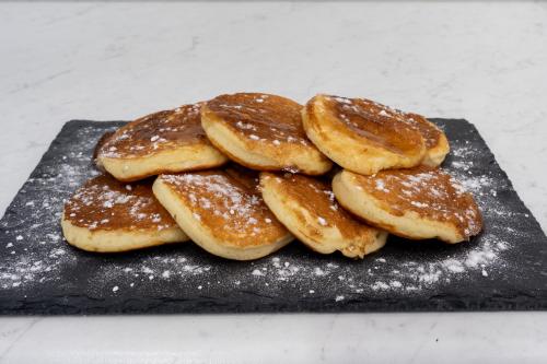 a pile of pancakes sitting on a black plate at Ideal House in Parga