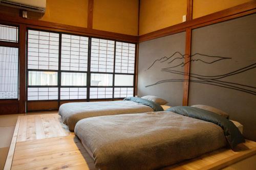 a row of beds in a room with windows at 町宿ORANCHI 