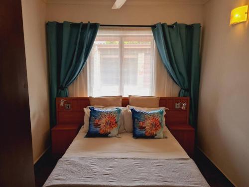 a small bed with green curtains and a window at Flamboyant Apartments in St Lucia
