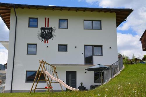 a white house with a playground in front of it at Appartement Wieshof in Neukirchen am Großvenediger