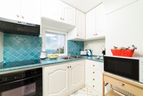 a kitchen with white cabinets and blue counter tops at Estate4home - Casa Darly in Positano