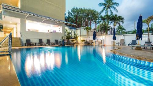 a large blue swimming pool with chairs and umbrellas at GP House Phuket Patong Beach in Patong Beach