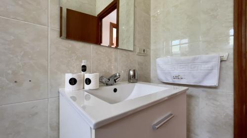 La salle de bains est pourvue d'un lavabo blanc et d'un miroir. dans l'établissement Villa Paco At Home, à Torrox
