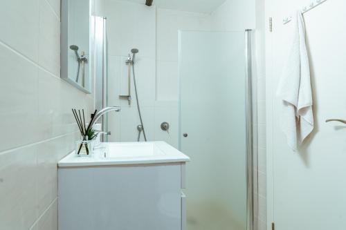 biała łazienka z umywalką i prysznicem w obiekcie Jabitat- Jaffa Boutique TLV w Tel Awiwie
