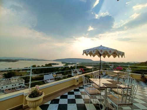 einen Balkon mit einem Tisch, Stühlen und einem Sonnenschirm in der Unterkunft Burj Baneria in Udaipur