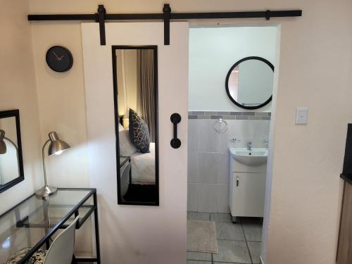 ein Badezimmer mit einem Spiegel und einem Waschbecken in der Unterkunft The Oak Potch Guesthouse in Potchefstroom